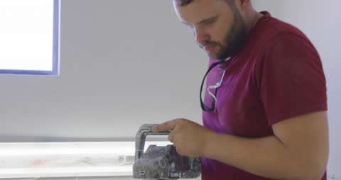 Craftsman Polishing Surfboard with Power Tool in Workshop