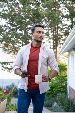 Man Relaxing Outdoors with Smartphone and Coffee Mug