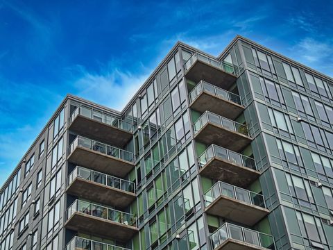Modern glass apartment condo building under vibrant blue sky