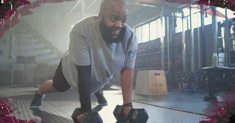 Man performing plank-style push-up with hex dumbbells in gym, building strength