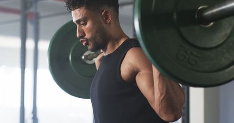 Man performing intense barbell back squat in gym