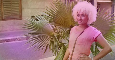 Confident Woman With Curly Hair Standing by Urban Palm Plant