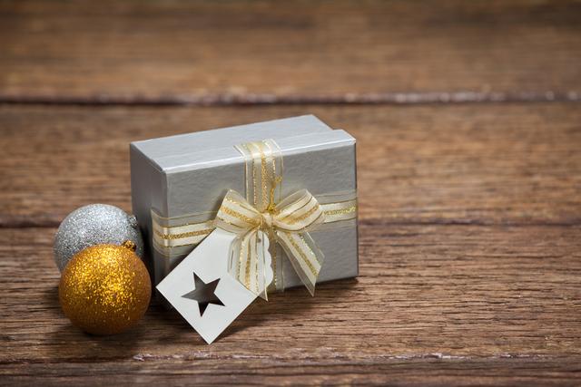 Wrapped Gift Box with Baubles on Wooden Table During Christmas - Download Free Stock Photos Pikwizard.com