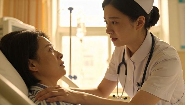 Compassionate nurse comforting patient at bedside in sunlit hospital ward with stethoscope