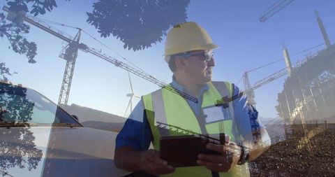 Site supervisor surveying construction with tablet double exposure cranes and wind turbine