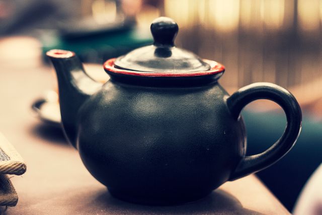 Vintage ceramic teapot sitting on a wooden table. This image evokes a sense of warmth and tradition, making it suitable for articles about tea culture, traditional kitchens, or rustic dining environments.
