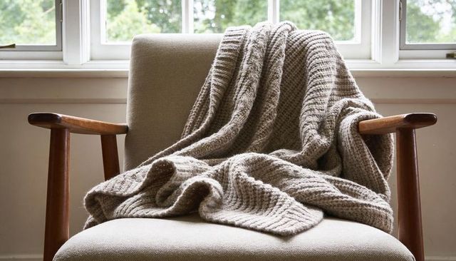 Sunlit mid-century armchair showing chunky knit throw for cozy interior