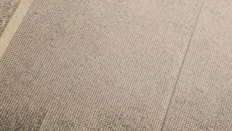Textured beige woven carpet close-up featuring seam lines, narrow border, grid dot pattern
