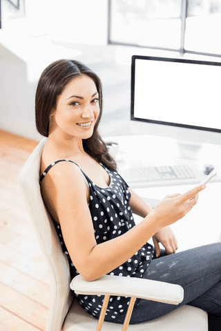 Confident young woman holding phone seated in bright workspace on transparent background