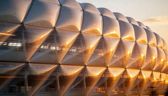 Golden sunset reflecting on modular etfe facade with curved cushions and geometric pattern
