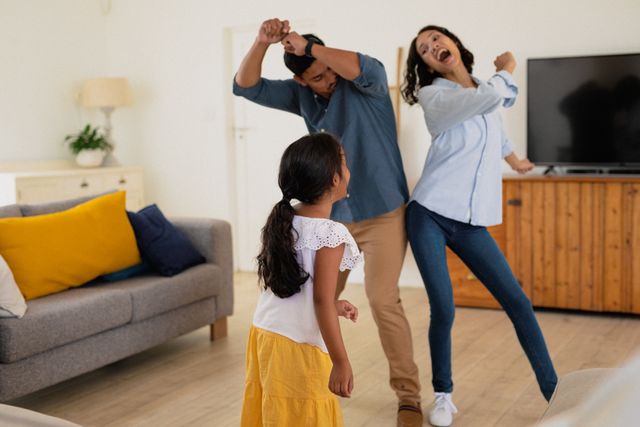 Happy hispanic daughter with parents dancing in living room. family spending time together at home.