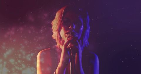 Singing vocalist gripping microphone under neon haze, moody concert atmosphere