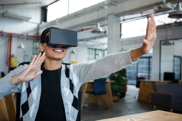 Businesswoman enjoying virtual reality experience in a modern office. Ideal for use in articles or advertisements about technology in the workplace, innovation, VR applications in business, and modern office environments.