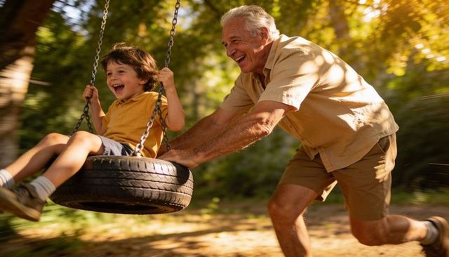 Grandfather Pushing Grandson on Tire Swing Laughing in Sunlit Park Bonding Moment