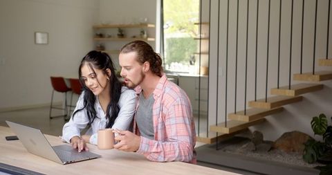 Young couple collaborating on laptop in modern minimalist kitchen