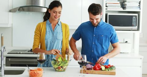 Happy Couple Preparing Fresh Salad in Modern Kitchen