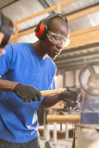 African american craftsman working wood lathe wearing safety glasses and hearing protection