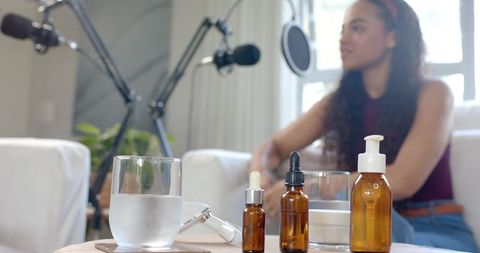 African american musician recording at home with microphones, guitar and amber bottles