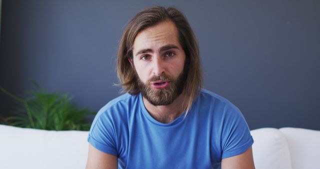 Thoughtful Young Man with Beard Sitting on White Sofa - Download Free Stock Images Pikwizard.com