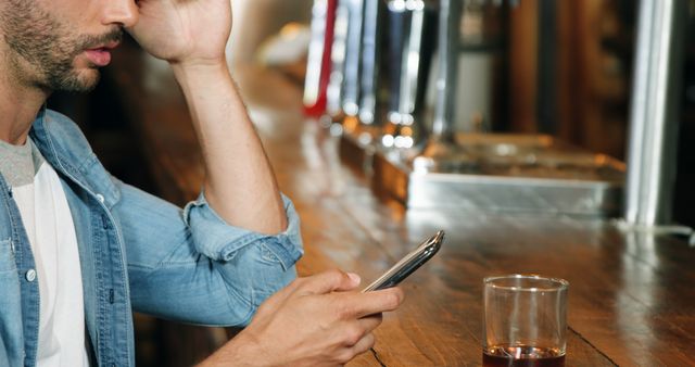 Worried Man Sitting at Bar with Smartphone and Drink - Download Free Stock Images Pikwizard.com