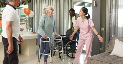 Female Nurse Welcoming Elderly Patient with Walkers in Therapy Center