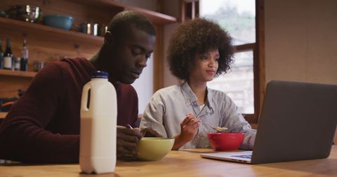 Young Couple Enjoying Breakfast While Working from Home on Laptop