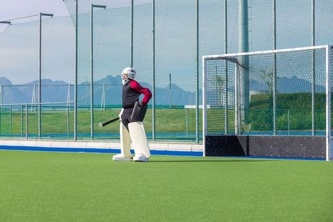 Field hockey goalkeeper in full gear on synthetic turf