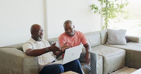 Father and son bonding over laptop on sofa
