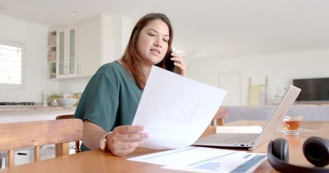 Busy Woman Working from Home with Documents and Laptop