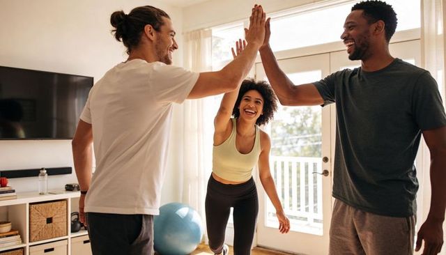 Friends high-fiving after home workout celebrating fitness in sunlit living room