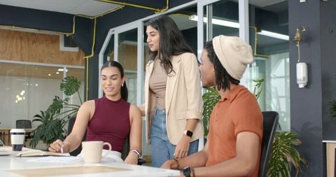 Multicultural team collaborating around notepad in modern open-plan office with plants