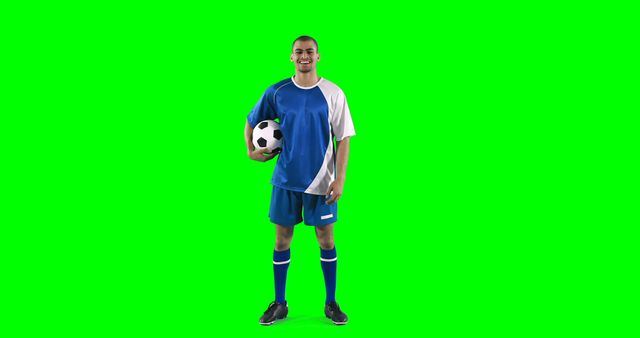 Smiling football player performing a skill against green background