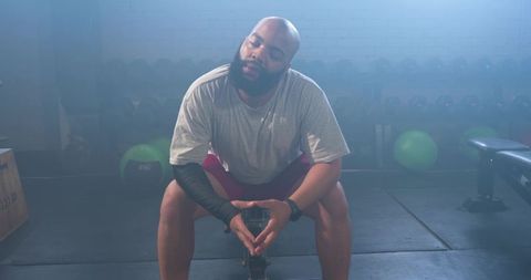 African american man resting on bench in gym after workout recovering from training