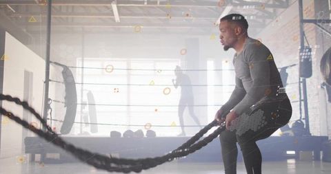 Male athlete swinging heavy battle ropes in industrial gym boosting strength and cardio