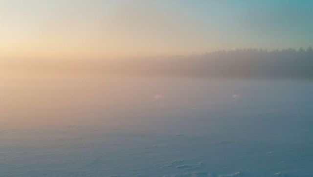 Misty frozen lake with pastel winter sky