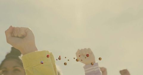 Women Raising Fists in Unity with Floating Emojis