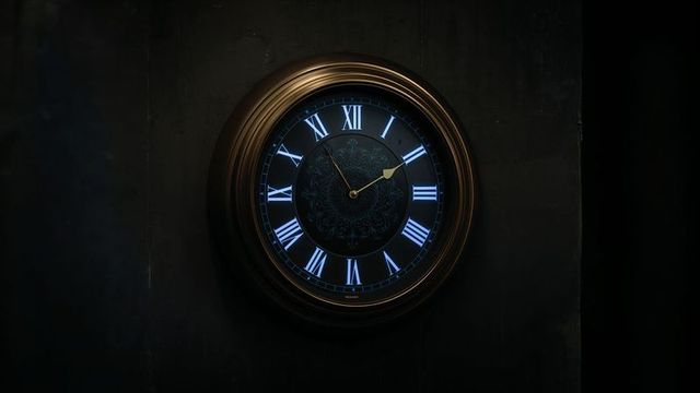 Antique bronze wall clock with glowing blue numerals