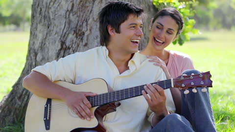 Couple Enjoying Guitar Music Relaxing in Nature