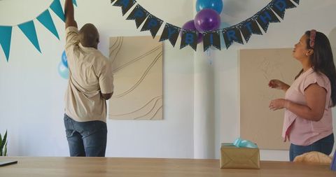 Diverse couple decorating for at-home birthday celebration
