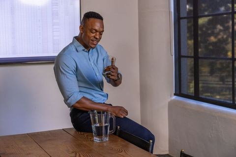 Confident businessman holding glass carafe in modern office