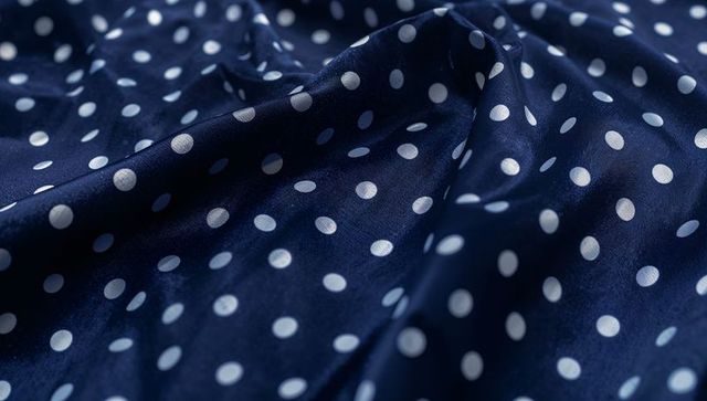 Navy blue polka dot satin fabric draping close-up showing shiny texture