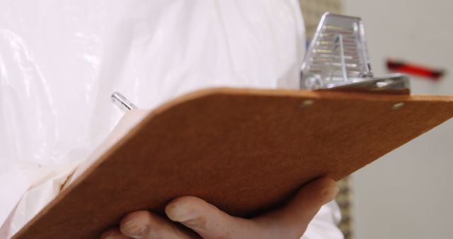 Closeup of Inspector Holding Clipboard and Pen in Protective Suit - Download Free Stock Images Pikwizard.com