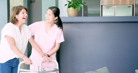 Nurse assisting senior woman using walker in living room