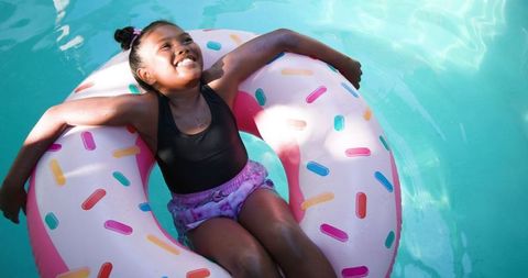 Smiling girl relaxing on donut float in pool