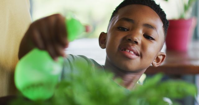 Young boy watering indoor plants with a green spray bottle, smiling and nurturing greenery. This image is perfect for homeschooling resources, educational content about gardening or environmental care, family and children activities, and promoting indoor hobbies.