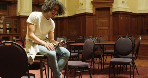 Young Man Using Phone in Serene Library Setting