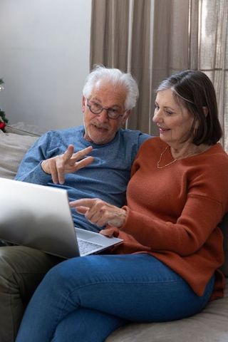 Senior Couple Relaxing with Laptop in Cozy Festive Living Room