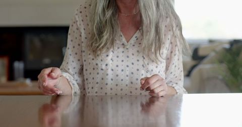 Senior Woman Tapping Fingers on Table in Thoughtful Contemplation