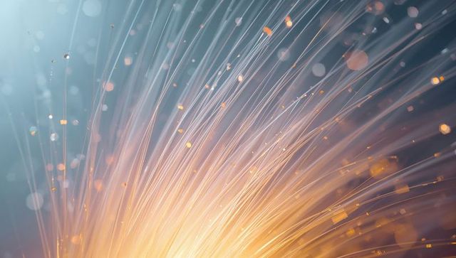 Glowing fiber optic light burst in amber and teal, radiant strands and floating bokeh