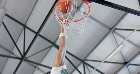 Basketball Player Dunking Ball in Thrilling Indoor Match